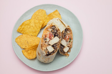 Mexican beef burrito on small plate with chips nachos