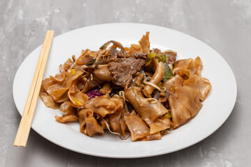Fried noodles with vegetables and beef in white dish