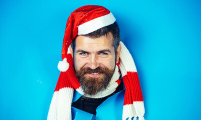 Smiling bearded man in santa hat and striped scarf looking through paper hole. Christmas sales.