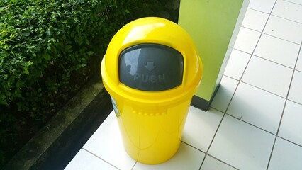 Yellow lid bin on the white floor. Outdoor.