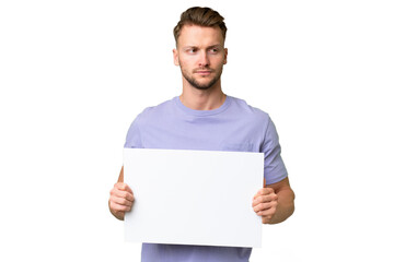 Young blonde caucasian man over isolated background holding an empty placard