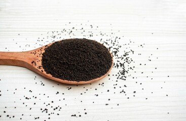 Closeup of Dry Camellia Sinensis Leaves or Tea Leaves in a Wooden Ladle Isolated on White Wooden Background with Copy Space