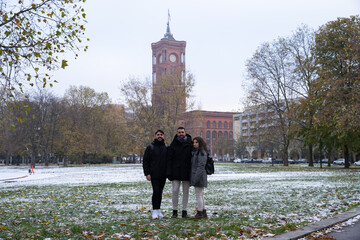 Group of friends or family in a Berlin park with the Rotes Rathaus in the background and all snowed...