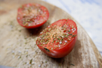 Tomaten mit Kräutern und Salz auf einer Holzplatte