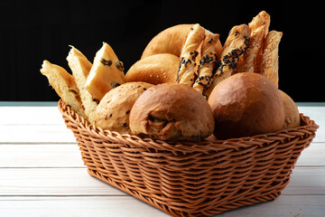 Bakery products in straw bread basket on wooden table