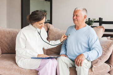 Obraz premium Woman nurse doctor gp holding stethoscope examining old senior 60s grandpa patient check heartbeat at home care checkup medical visit