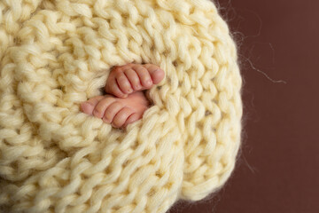 small legs of a newborn on a yellow background. knitted scarf yoke