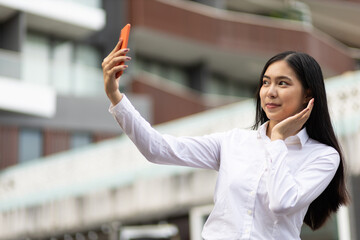 Fototapeta premium Pretty Asian woman holding smartphone taking selfie.