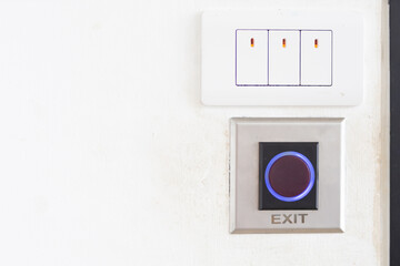 Close up of the light switch and exit button on the wall next to the door.