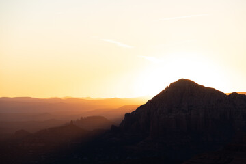 Dramatic sunset over the mountains of Sedona Arizona with layers of mountains in the distance.