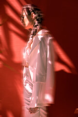 Fashionable woman with white braids in white elegant suit and high heels with motion blur effect.