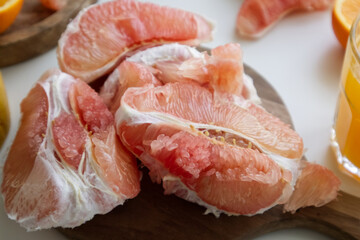 Pomelo in a cut on a wooden stand near a glass of freshly squeezed juice and oranges