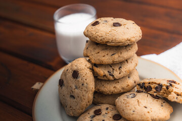 Cookies pile on a plate with a glass of milk