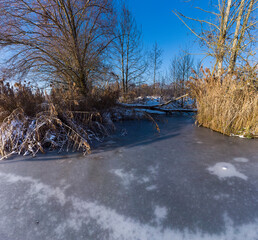 Verschneites see ufer mit blauem Himmel. Natürliche Winterlandschaft. Beautiful frozen lake with warm colours at sunset. Seasonal. Winter. Frosty snowy lake shore.