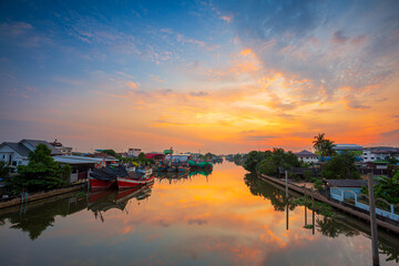 Fototapeta premium Evening view of the port and city of thailand,City view of Bangkok, Thailand There is the Chao Phraya River on the right and the pier on the left with sunset light in the sky. There are blue, purple, 