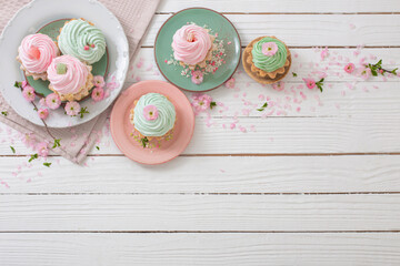 pink and green cupcakes with spring flowers on white wooden background