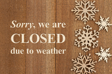 Sorry we are closed due to weather sign with snowflakes on weathered wood
