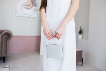 Woman in elegance white dress. Girl in photostudio. Beautiful shining bag. Close up.