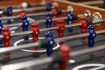 Close-up plastic players in table football in entertainment center. Soccer table with red and blue...