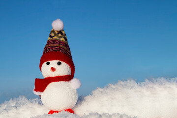Obraz premium A happy snowman stands in the snow on a blue background. Winter fairy tale
