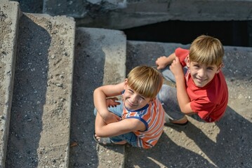 Two children are sitting on the steps of an abandoned building, a concept of the life of street children orphans.