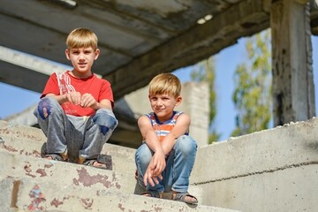 Two children are sitting on the steps of an abandoned building, a concept of the life of street...