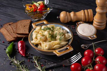 boiled dumplings with sour cream and gray bread, on a black background