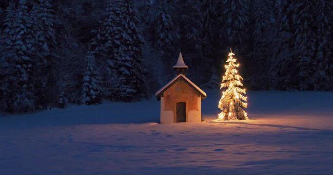 Beleuchteter Weihnachtsbaum mit Kapelle bei Nacht, Winterlandschaft, Bayern, Deutschland