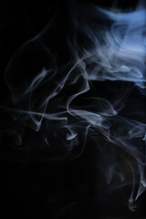 Graceful swirls of white smoke isolated from black background. Close-up of vapor. Soft focus and texture from vintage Helios 44m-4 lens. Abstract graphic design asset. Vertical copy space.