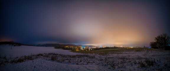 night landscape of a snowy field and a city  with lights on the horizon
