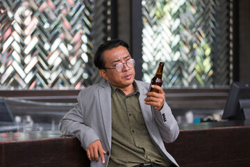 Asian businessman at bar counter with drinking beer