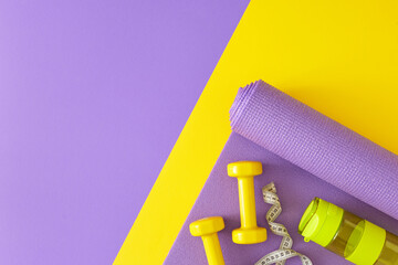 Creative sports concept. Top view composition of dumbbells, exercise mat, tape measure, bottle of...