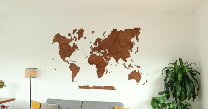 Wooden world map wall decoration. Elegant and simple interior decor for travel, geography, voyage enthusiasts. Modern living room with wooden ornament. 4K HD. High quality 4k footage