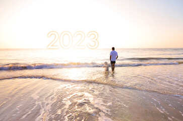 Fototapeta na wymiar man with his friend dog Watching the sun rise by the beach on New Year's Day 2023