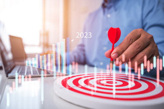 Male Hand Holding Darts Aim At The Target With Business Graph On Screen , Business Plan Growth Year 2023