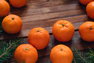 Fototapeta na wymiar Fresh ripe clementines or mandearine oranges and fir tree branches on a dark woden board. Christmas food. Copy space.
