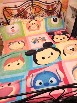 Disney Tsum Tsum Blanket On An Adult Double Bed In A Bedroom With Pink Flowery Wallpaper  And White Furniture 