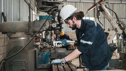 Industrial engineers inspect and perform maintenance on the machines at factory machines.