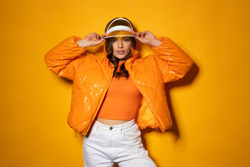 Beauty latino female with hood and jacket on orange background with shadow.