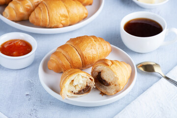 A freshly baked French Croissant, coffee, butter and jam