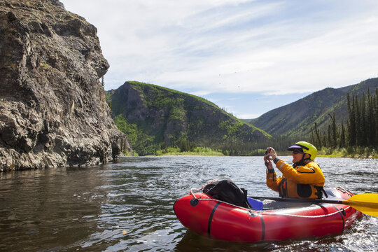 Woman photographing from her Packrafting on the Charley River in summertime, Yukon–Charley Rivers National Preserve; Alaska, United States of America