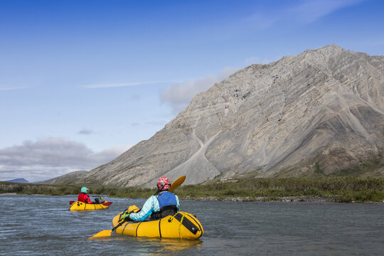 Two women paddle down the Canning River on a sunny late summer day through the Brooks Range, Arctic National Wildlife Refuge; Alaska, United States of America