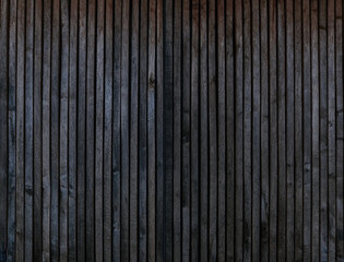 Auffällige, markante und rustikale Holzwand aus dunklen Planken als Hintergrund, low key