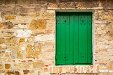 Fototapeta na wymiar Brick dwelling with closed green shuttered window