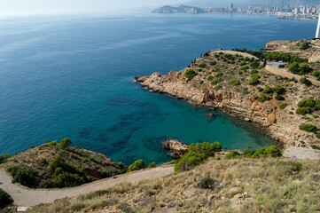 Vistas desde el mirador de la ciudad de Benidorm con los altos edificios al fondo desenfocados y el agua cristalina de la cala enfrente.