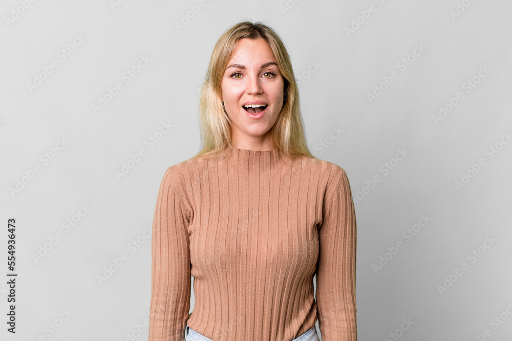 Wall mural caucasian blonde woman looking happy and pleasantly surprised