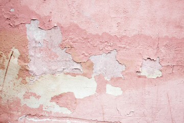 Pink rough painted wall of the house with pieces of fallen plaster pink city wallpaper