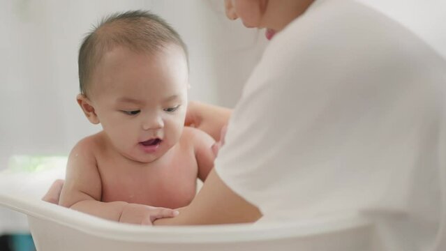 Closeup view of young Asian mother is Bathing with her newborn baby In Bathtub at home.Concept of newborn,baby,parenthood,motherhood,childhood,New life,maternity,love,new family member
