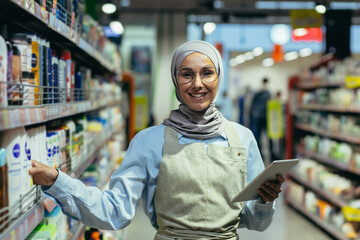 Portrait of a female saleswoman in a hijab, a salesperson in a household chemicals department is...