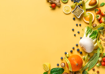 Set of fresh vegetables, fruits and berries for healthy diet food on yellow background with measuring tape, copy space top view. Dietary